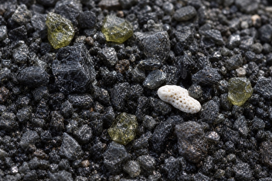 Close-up texture of black volcanic sand, ground down from basalt