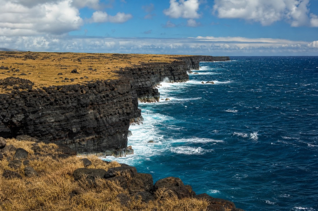 Wave-battered lava cliffs near Ka Lae, the same coast that produces the island's black sand