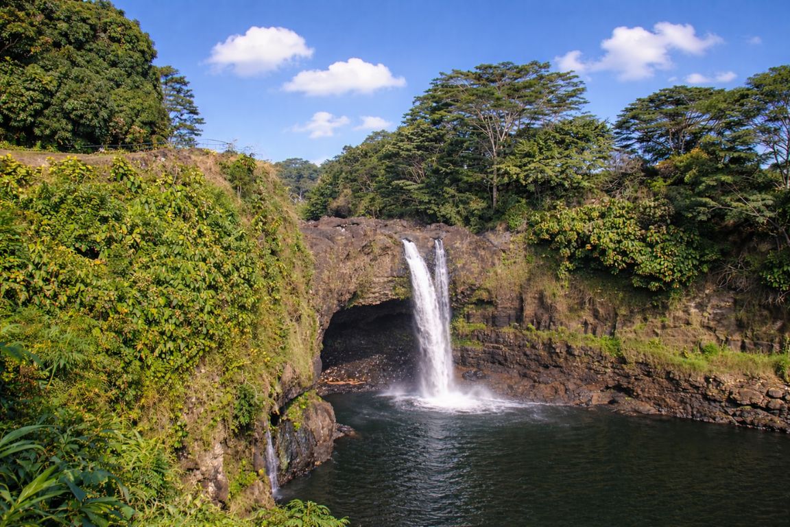 Peʻepeʻe Falls waterfall in Hilo Hawaii flowing into a calm pool surrounded by lush tropical greenery, visited during a guided tour with Hilo Tours